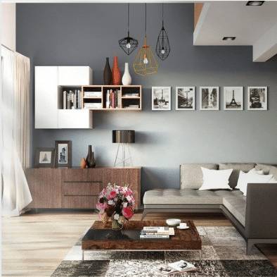 Modern living room with a gray sectional sofa, wooden coffee table, contemporary light fixtures, and curated wall art—perfect for Airbnb SEO photos. Bookshelves line the gray wall, while a vase of flowers adds a welcoming touch to the table.