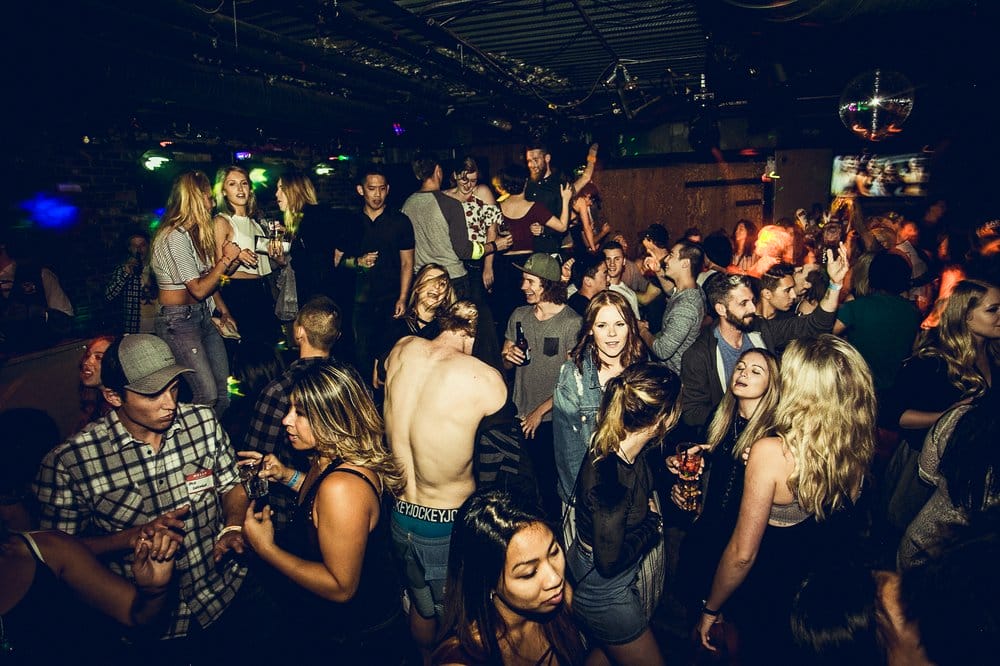 A crowded nightclub buzzes with activities Whistler is known for—people dancing, talking, and holding drinks; dim lighting and a lively atmosphere fill the room.