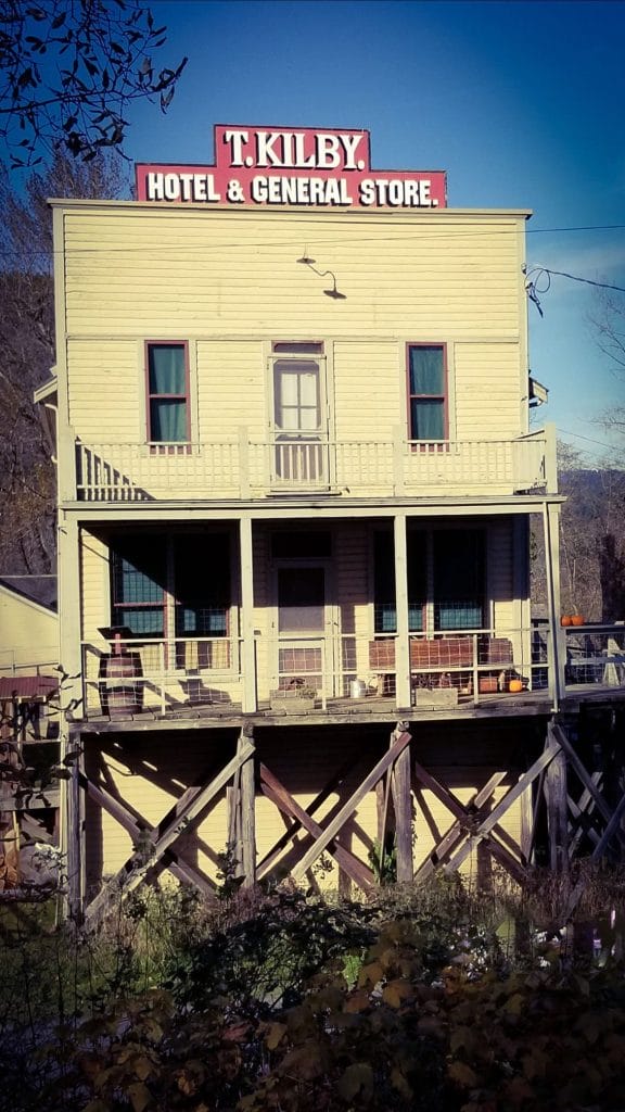 A two-story yellow wooden building on stilts with a sign reading "T. Kilby Hotel & General Store" on the roof, this spot is one of the unique things to do in Harrison Hot Springs.