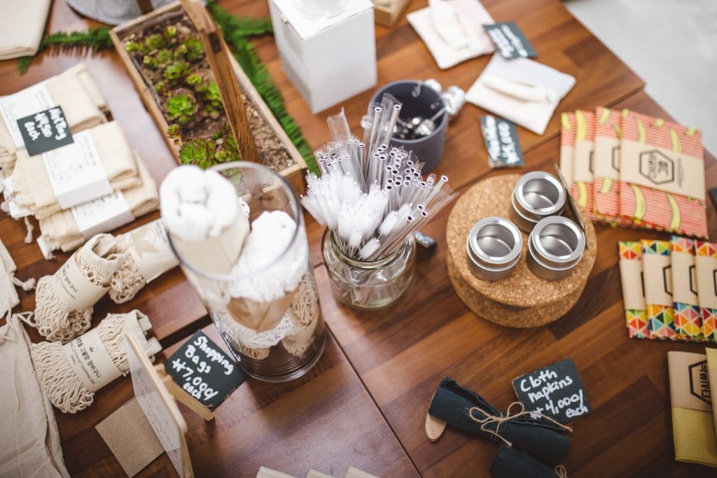 A selection of eco-friendly products, perfect for your eco-friendly Airbnb, including reusable straws, cloth bags, small tins, and other sustainable items arranged neatly on a wooden table.