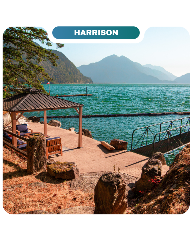 A lakeside patio with a gazebo, benches, and dock overlooks turquoise water and distant mountains under a clear sky at Harrison—perfect for relaxing and enjoying the Lifty Life.