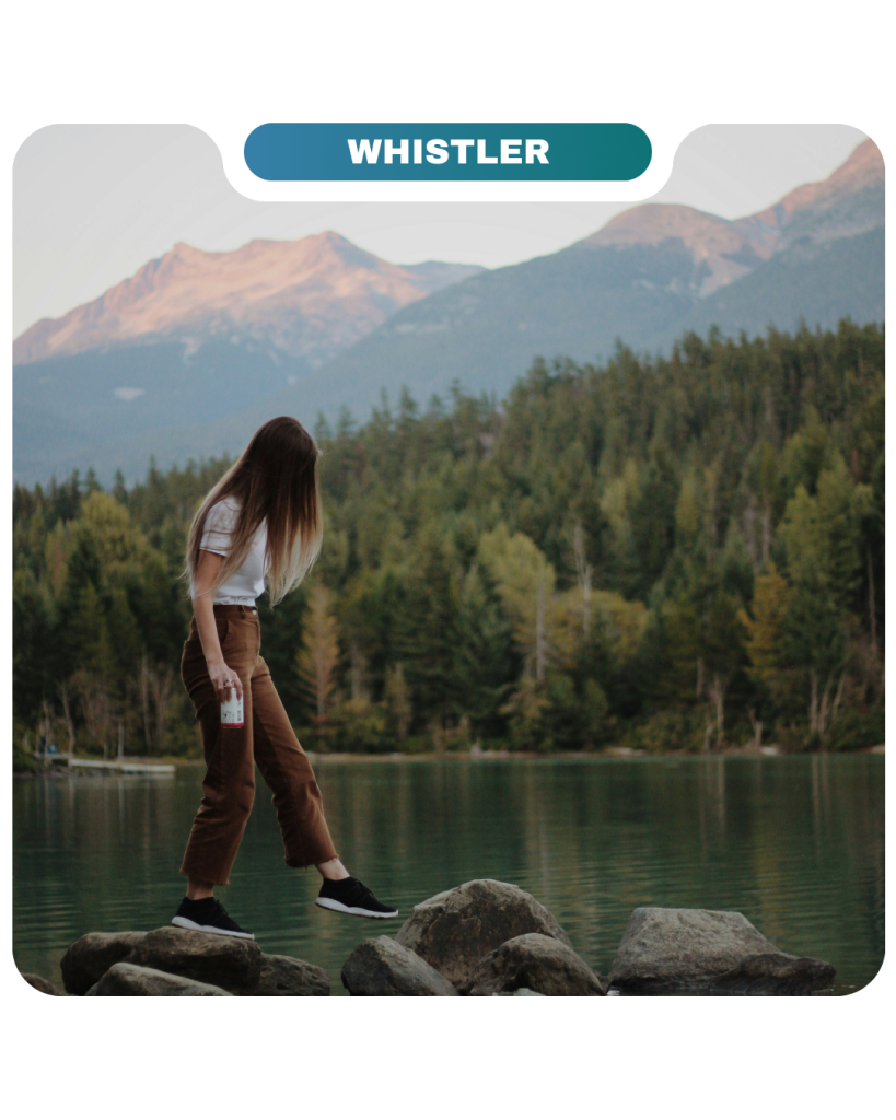 A person stands on rocks by a lake surrounded by trees and mountains, with a "Whistler" label at the top and a subtle nod to Lifty Life adventure in the fresh mountain air.