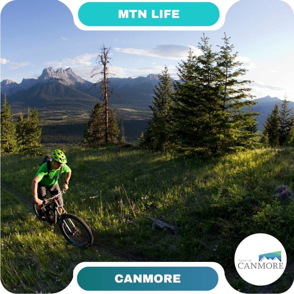 A mountain biker rides along a grassy trail with trees and mountains in the background under a clear sky, inviting guests to experience "MTN LIFE" and explore top destinations in Canmore.