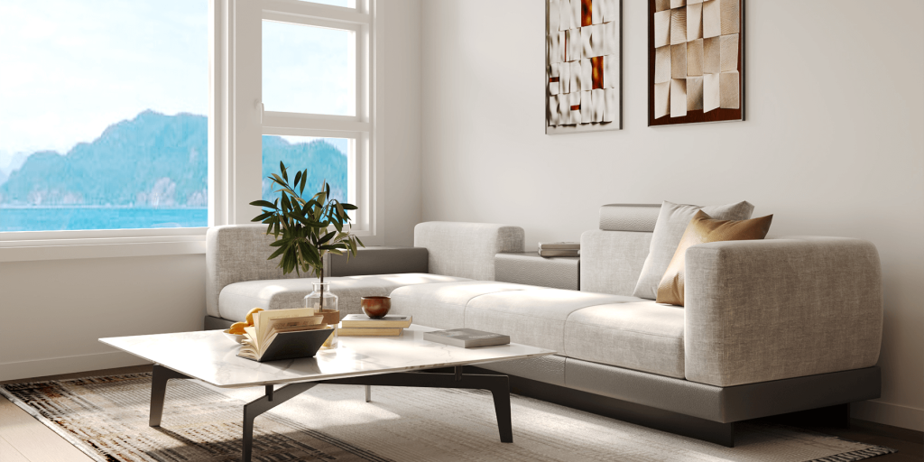 A modern living room at Cultus Grove features a large light-gray sofa, coffee table with books and a plant, expansive window with mountain view, and striking abstract wall art.